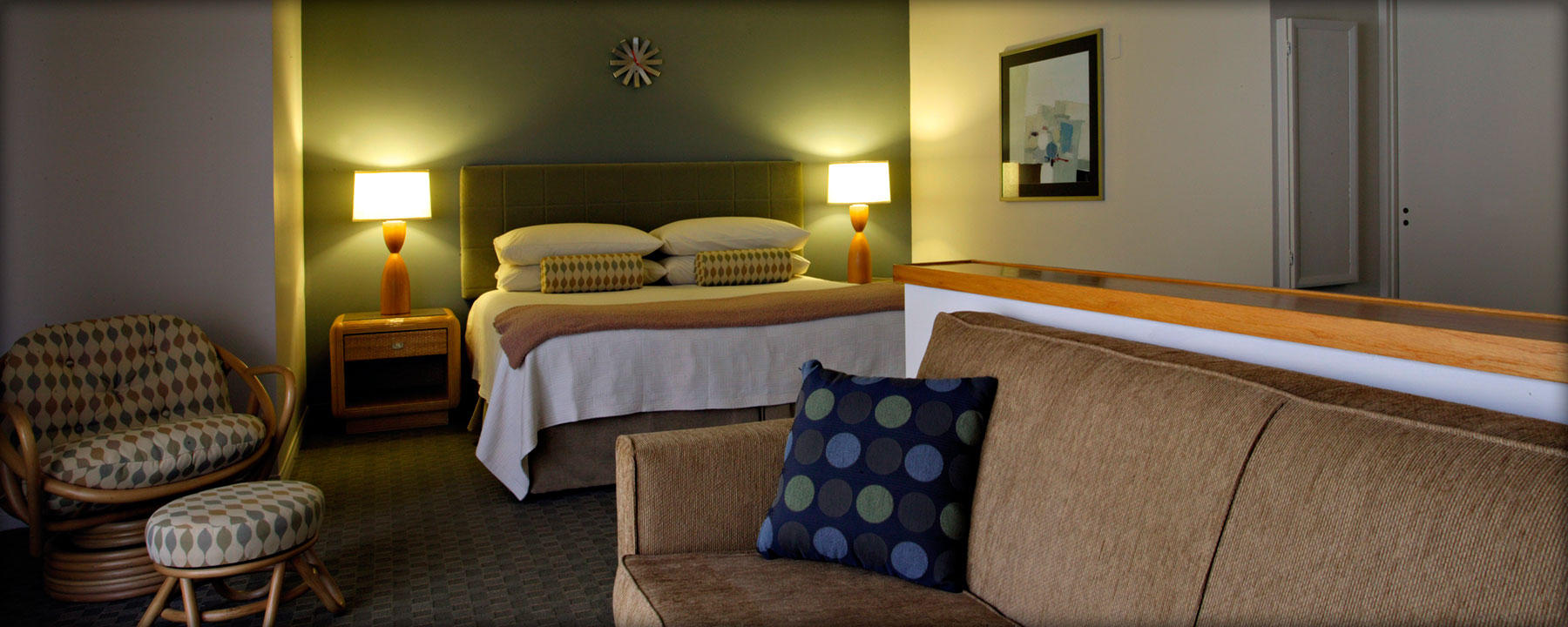 A hotel room with a bed, sofa, chair, and nightstand.